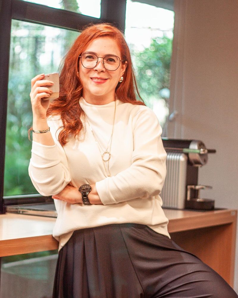 Dra. Kelly Marques Tavares sorrindo, com uma xícara de café no escritório